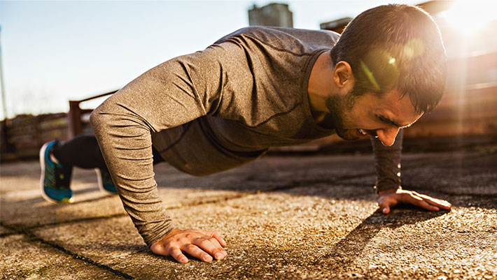 Man working out outside in the sun in push up position