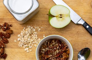 Cutting board with an apple, raw oats and pecans